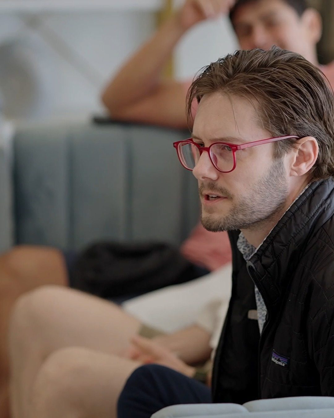 Shane Dixon in red glasses, listening during a group discussion.